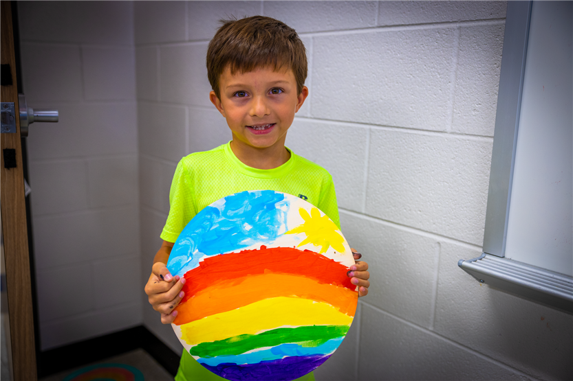 A boy holds up a piece of artwork